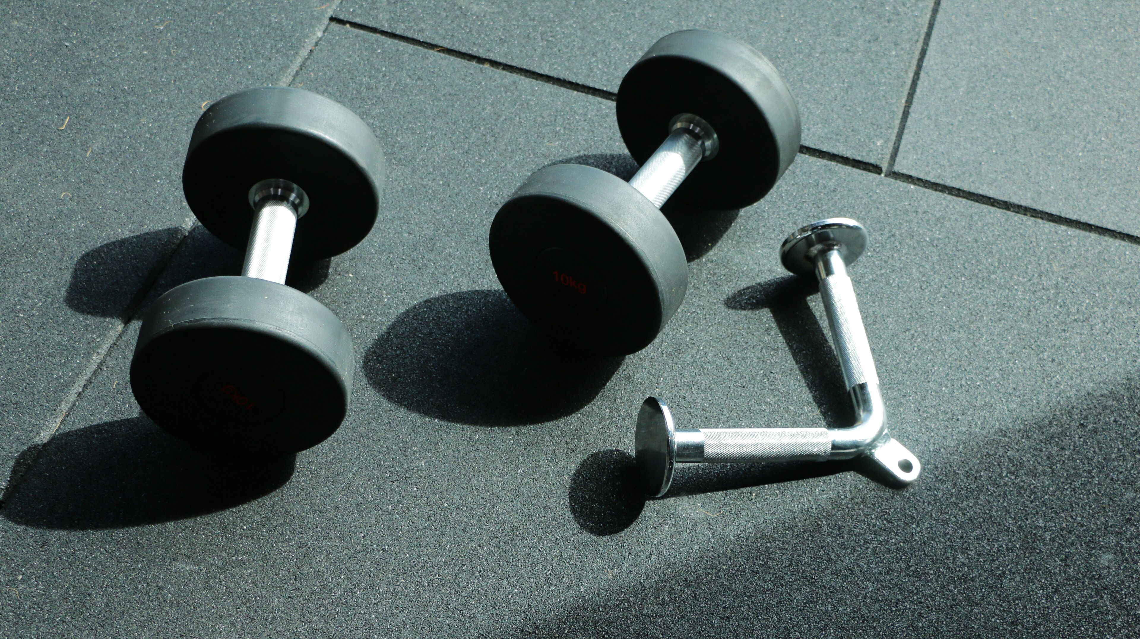Two dumbbells and a weight plate on a textured floor.