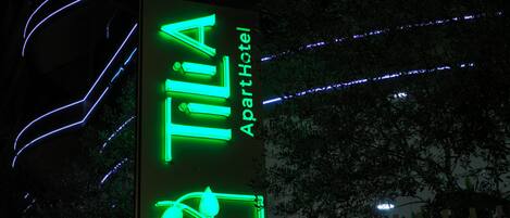 Ein Neon-Schild für 'TILIA ApartHotel' mit einem stilisierten 'T' und einem Fahrrad-Symbol.