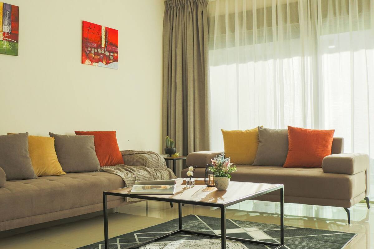 Uma sala de estar com dois sofás, uma mesa de centro e uma mesinha lateral com uma planta.