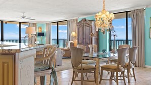 A dining area with a glass table, chairs, and a chandelier.