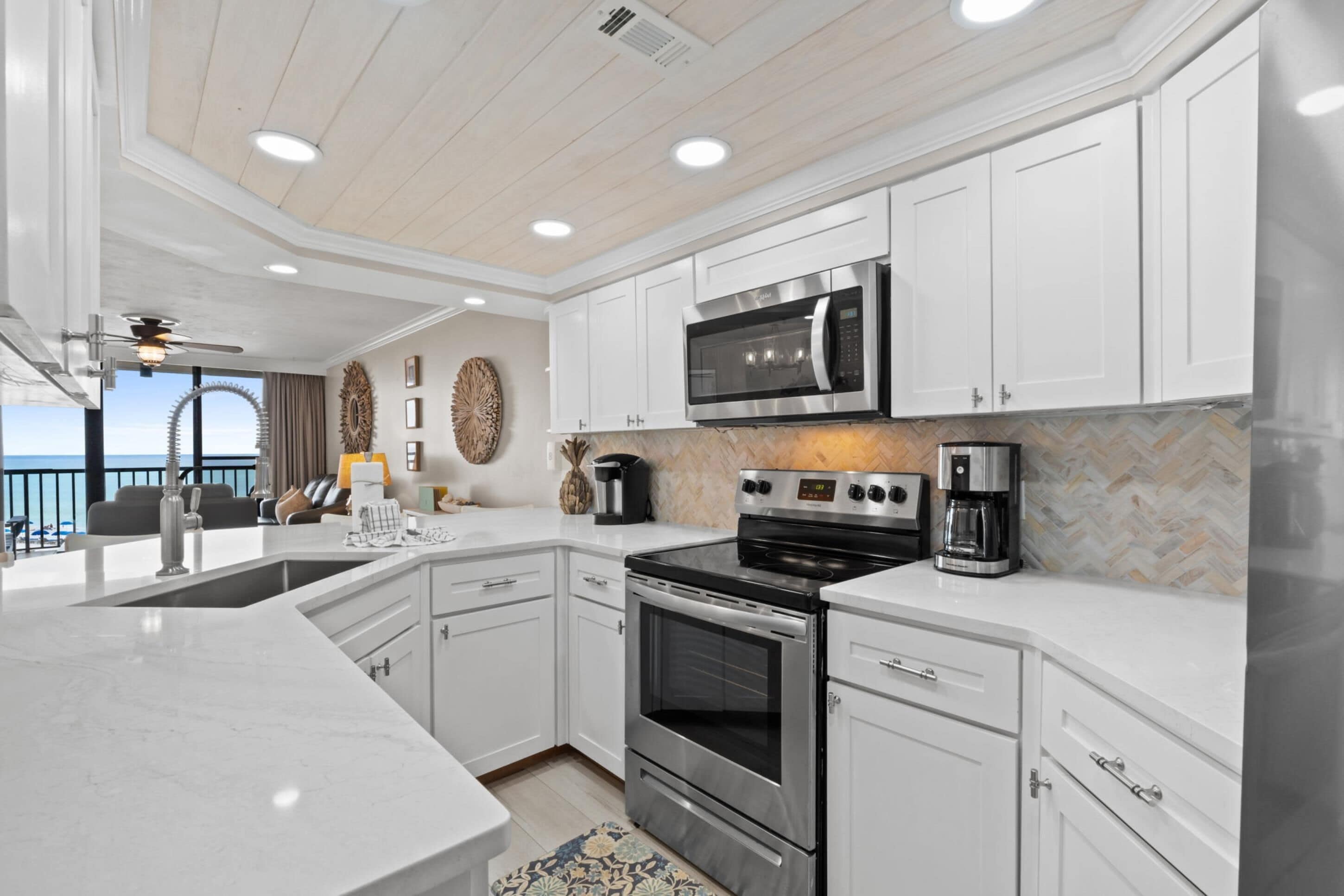 A modern kitchen with white cabinetry, stainless steel appliances, and a herringbone tile backsplash.