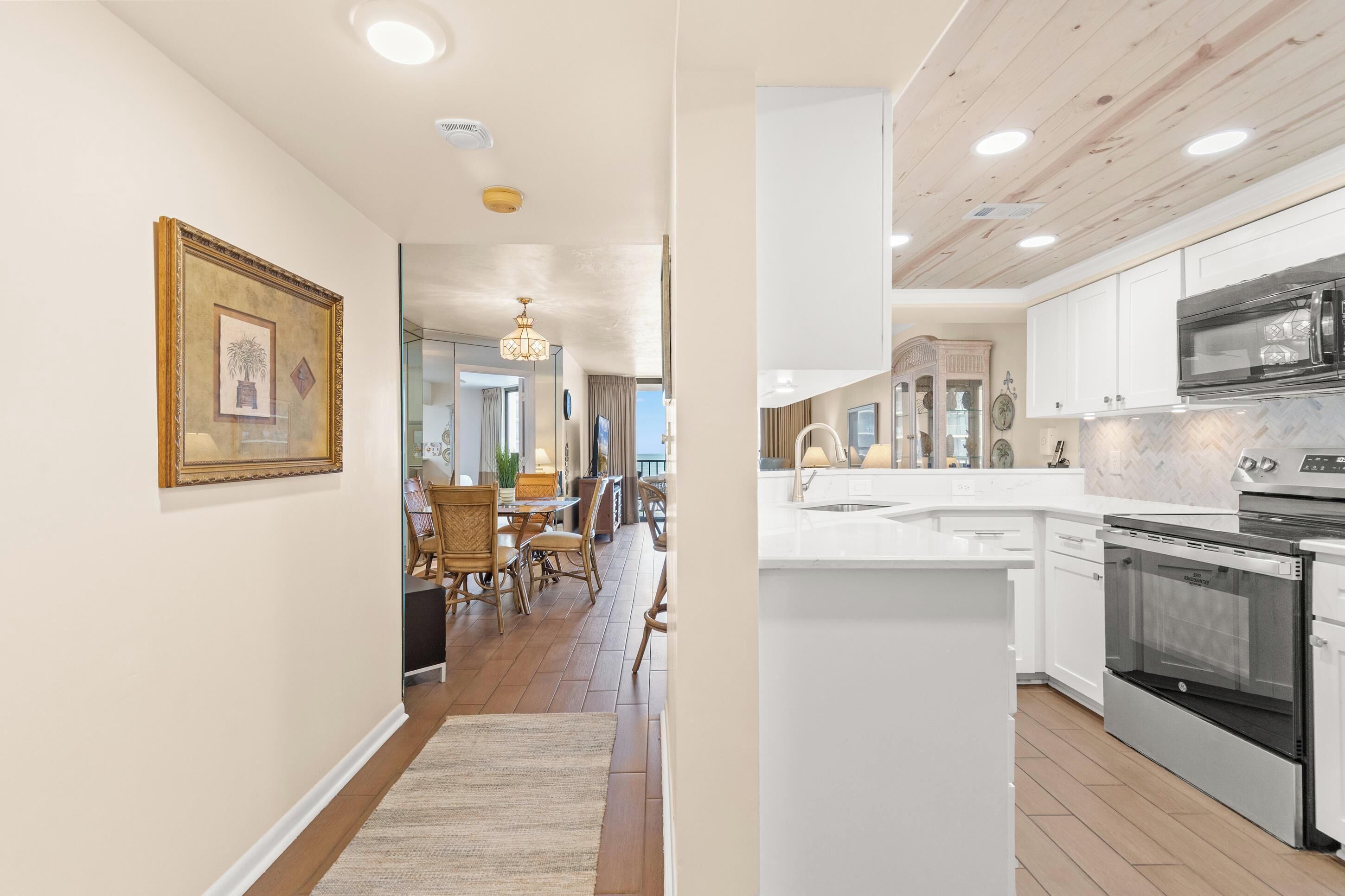 A modern kitchen with white cabinets, a stainless steel oven, and a marble countertop.