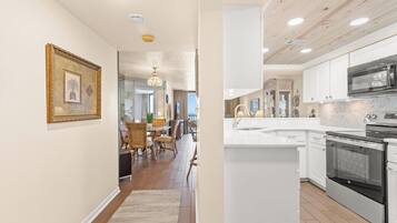 A modern kitchen with white cabinets, a stainless steel oven, and a marble countertop.