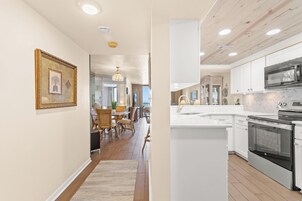 A modern kitchen with white cabinets, a stainless steel oven, and a marble countertop.