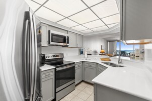 Eine moderne Küche mit Edelstahlgeräten, einer Mikrowelle, einem Backofen und einem großen Fenster mit Aussicht.