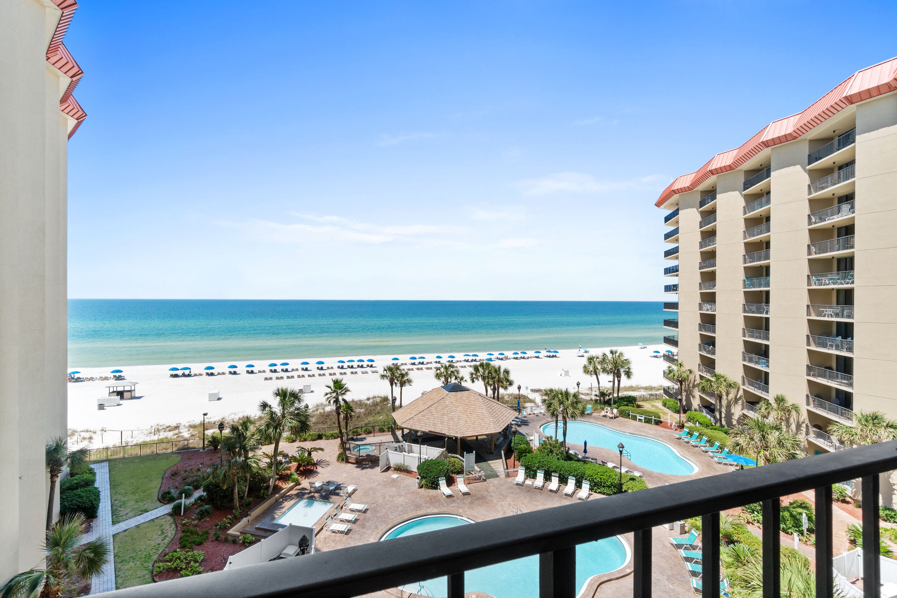 A hotel with a pool, beach, and ocean view.