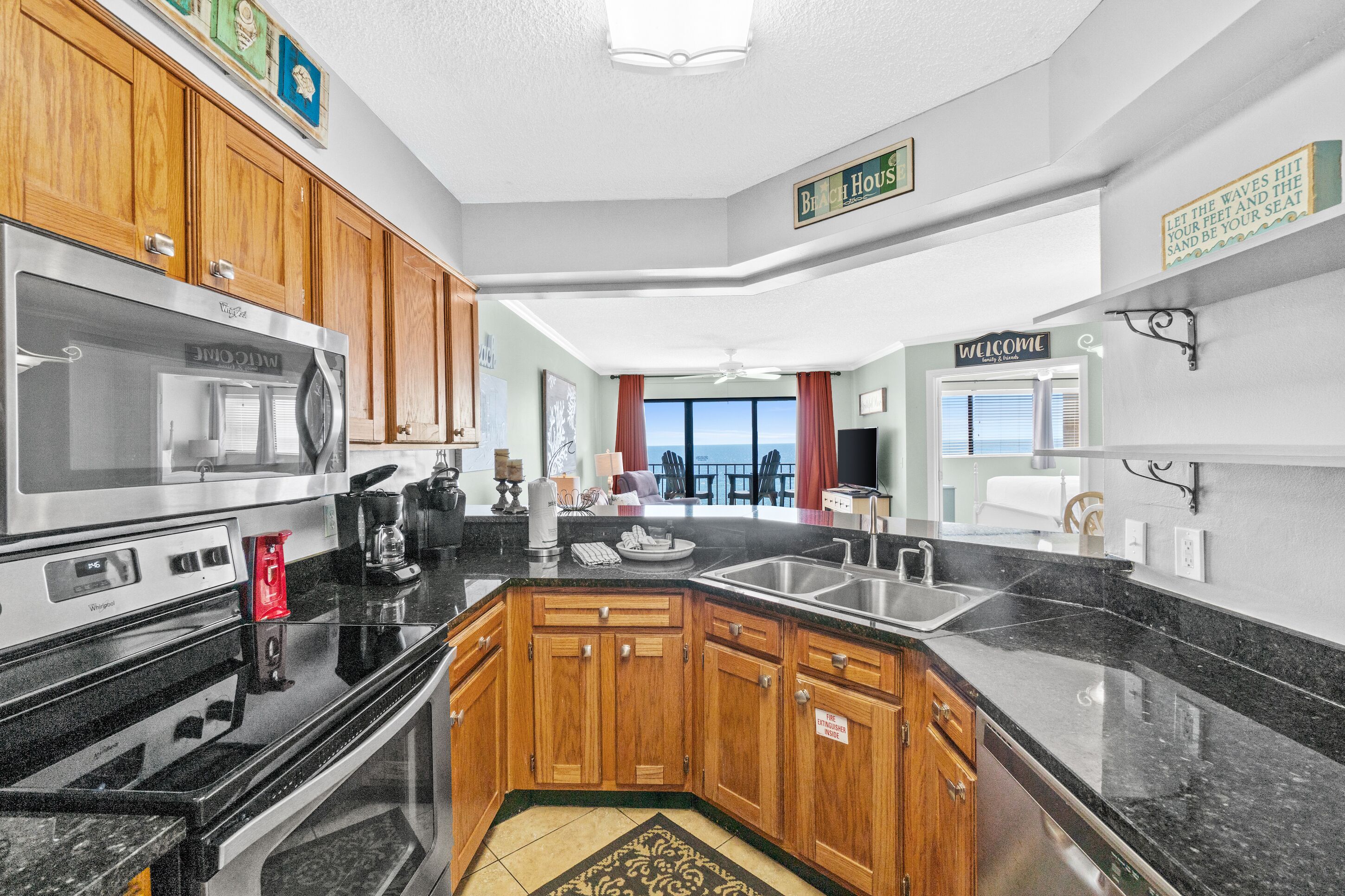 A modern kitchen with wooden cabinets, a stainless steel refrigerator, and a black countertop.