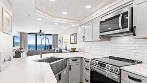 A modern kitchen with a large island, stainless steel appliances, and a view to the outside.