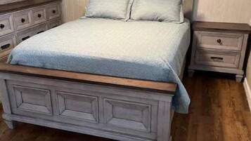 Un dormitorio con cama, mesitas de noche y cómoda.