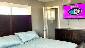 Ein Schlafzimmer mit Bett, Wandfernseher und Fenster.