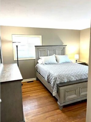 Cozy retreat with a comfortable bed, nightstand, and window with blinds.
