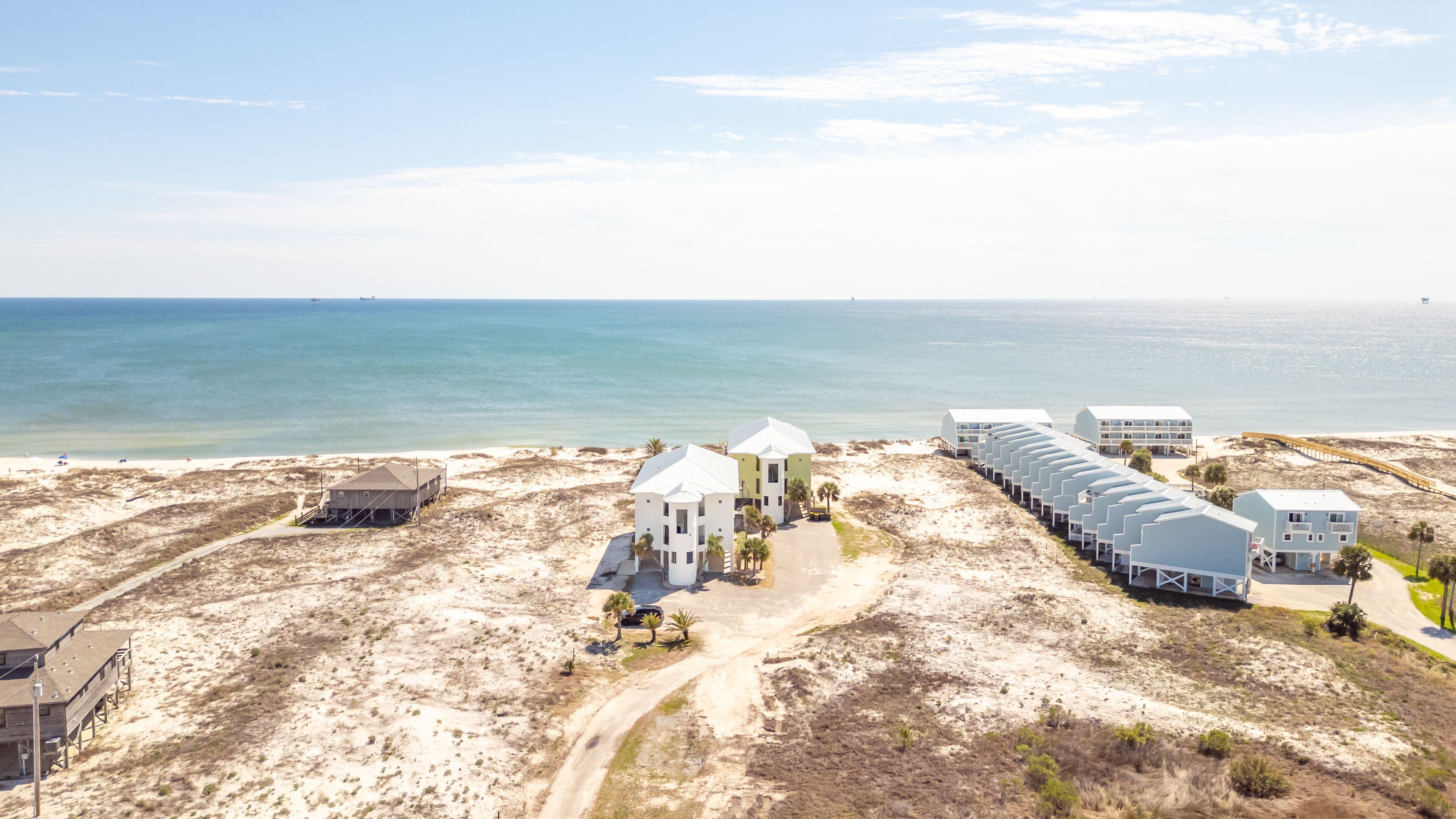 Un hôtel situé sur la côte, composé de plusieurs bâtiments, avec une plage et une vue dégagée sur l’océan.