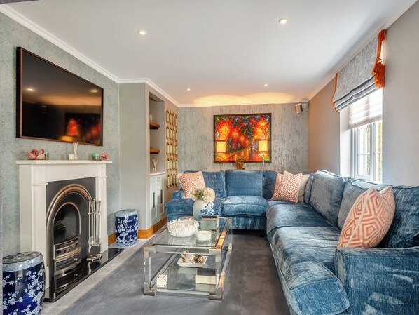 A living room with a fireplace, a large painting, a blue sofa, and a coffee table.
