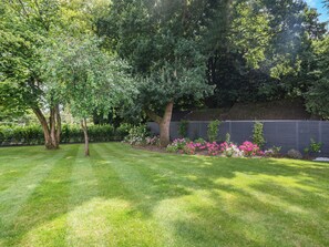 Un jardin bien entretenu, agrémenté de diverses plantes à fleurs et d’arbres.