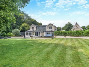 A large house with a spacious lawn, a conservatory, and a satellite dish.