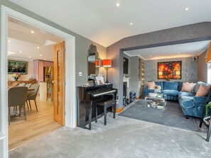 Un salon moderne avec un piano, un canapé bleu et un coin repas comprenant des chaises et une table.