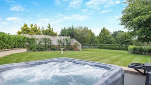 A hot tub in a backyard with a lawn, trees, and a wooden fence. - Perfect for a special occasion or get-together. (Medstead, near Alton)