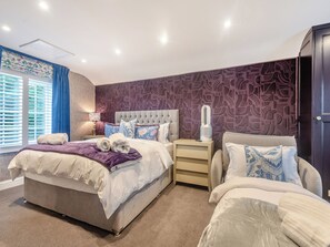 A bedroom with a bed, bedside tables, a nightstand, a lamp, and a window with blinds.