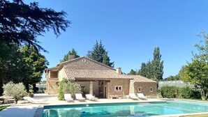 A stone villa with a swimming pool, lounge chairs, and a garden. - Mas Provençale Entouré de Pommiers, Piscine et Terrain de Tennis (Cavaillon)