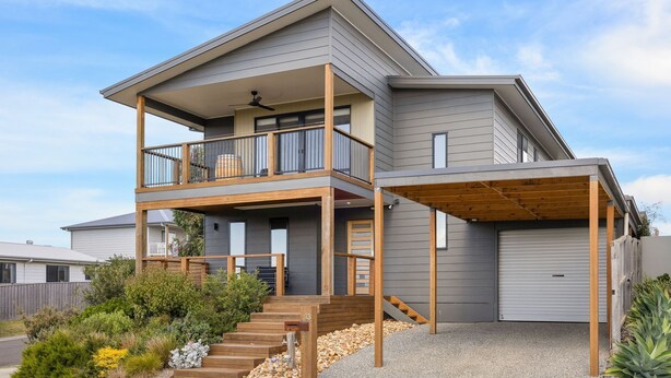 A two-story house with a balcony, a covered porch, and a garage. - The Beach House on Pembrey (Cowes)