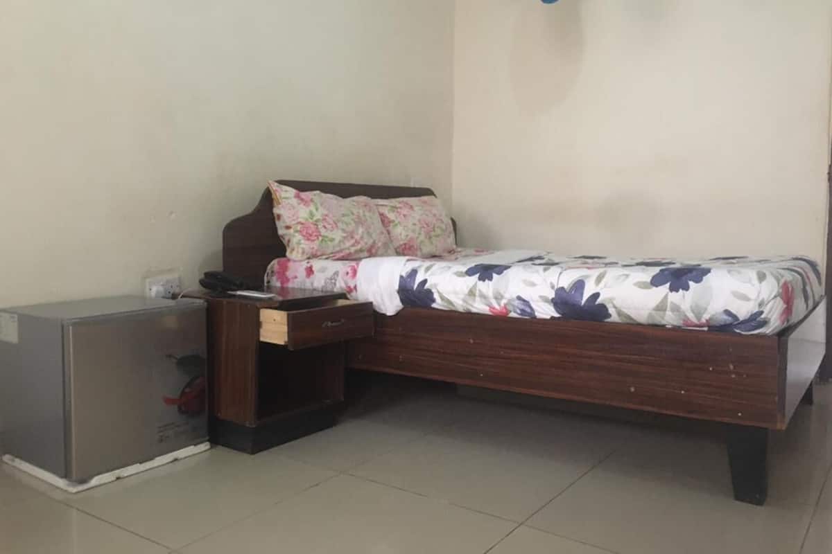 A bedroom with a wooden bed, a nightstand, a dresser, and a small cabinet.