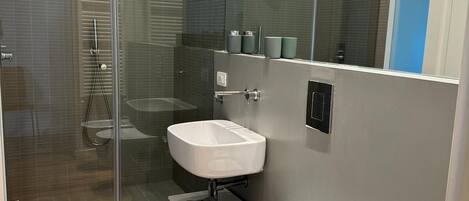 Un baño moderno con cabina de ducha de vidrio, dos lavamanos, un inodoro y un bidé.