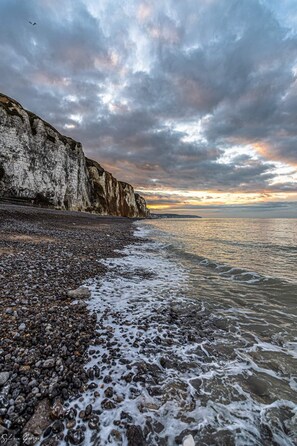 A rocky beach with a cliff and ocean.
