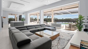 A modern living room with a sectional sofa, a glass coffee table, and a view of a lake.