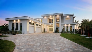 A modern two-story house with a paved driveway, large windows, and a well-maintained lawn.
