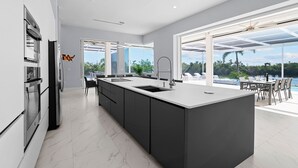A modern kitchen with a large island, built-in appliances, and a view of the outdoors.