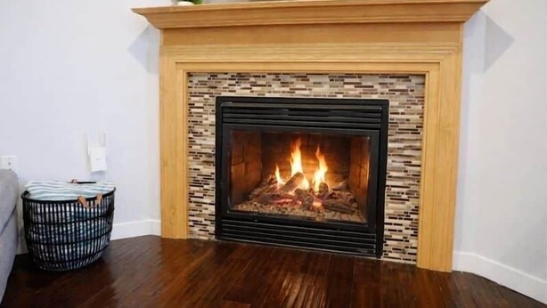 Una chimenea con un revestimiento de azulejos y un televisor encima.