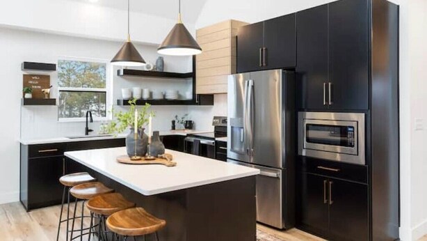A modern kitchen with black cabinetry, stainless steel appliances, and a central island with stools. - Lux Lake View Retreat: Table Rock View, Hot tub, Pool, Pet Friendly (Hollister)