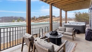 A covered outdoor seating area with wicker furniture, a round table, and a hot tub. - Lux Lake View Retreat: Table Rock View, Hot tub, Pool, Pet Friendly (Hollister)