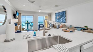 Eine moderne Küche mit einer großen Kochinsel, ein Essbereich mit Blick und ein Balkon mit Sitzgelegenheit.