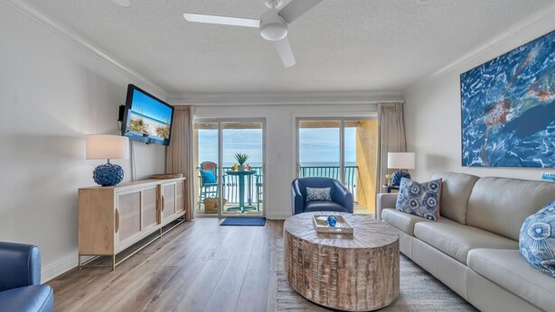 Ein Wohnzimmer mit Fernseher, Sofa, Couchtisch und einem Balkon mit Meerblick.