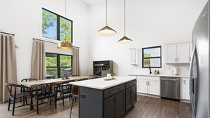 Une cuisine moderne dotée d’un îlot central, de meubles de couleur sombre et d’appareils électroménagers en acier inoxydable.