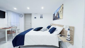 A bedroom with a bed, bedside table, and a desk with a chair.