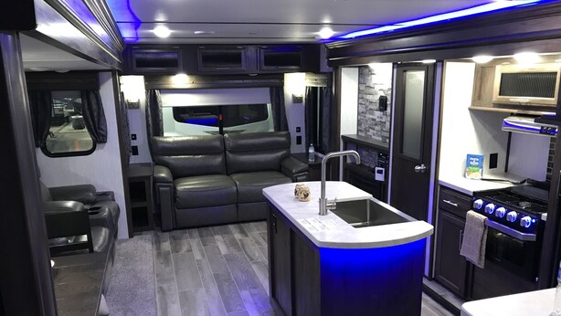 A compact kitchen with a central island, a built-in oven, and a stove. - 26FT CAMPER IN THE BEST FISHING/HUNTING SECRET IN SC (Iva)