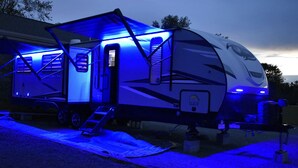 A recreational vehicle with a covered living area and a ladder leading to the entrance. - 26FT CAMPER IN THE BEST FISHING/HUNTING SECRET IN SC (Iva)