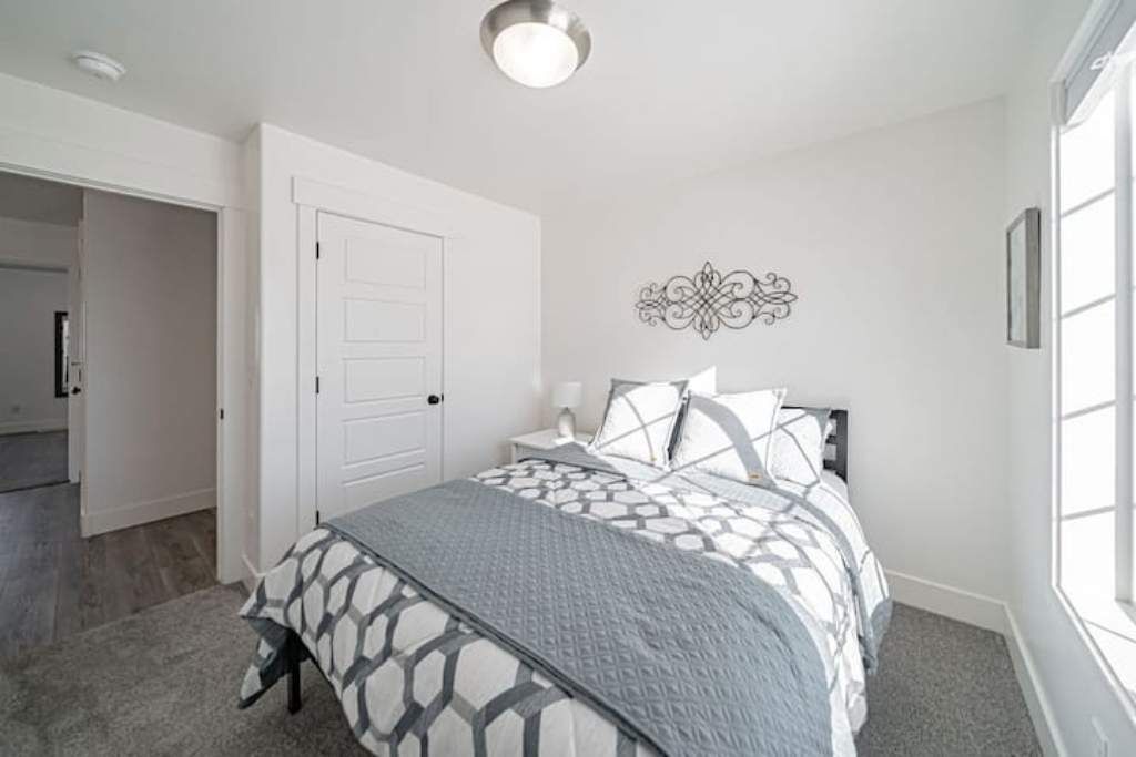 Une chambre à coucher avec un lit, une porte, un élément de décoration murale et une fenêtre.