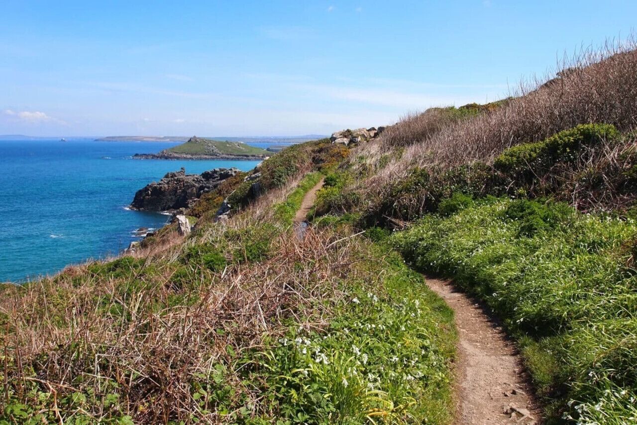 Un camino costero con vistas despejadas al océano y una isla distante.