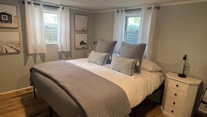A bedroom with a bed, bedside tables, and a window. - Adorable beach house - 5 min walk to private beach (Wareham)