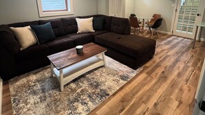 A living room with a sectional sofa, a coffee table, and a rug. - Adorable beach house - 5 min walk to private beach (Wareham)