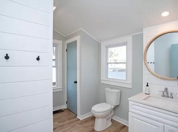 A bathroom with a toilet, sink, and mirror.