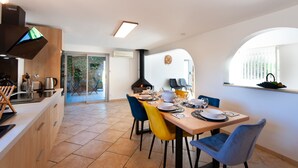 Een moderne keuken met een eethoek, met een groot raam, een inbouwfornuis en een tafel gedekt voor vier personen.