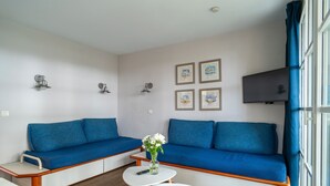 En moderne stue med en blå sofa, et lille hvidt bord og en vase med blomster.
