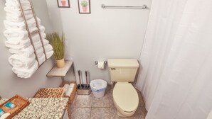 Ein Badezimmer mit Toilette, Handtuchhalter und zwei gerahmten Bildern an der Wand.