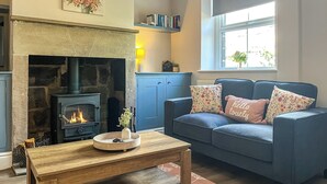 Ein Wohnzimmer mit Kamin aus Stein, einem blauen Sofa und einem Couchtisch aus Holz.