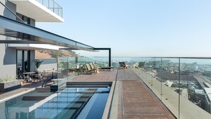 A modern rooftop pool area with a glass balustrade, wooden deck, and outdoor seating. - Bright Studio With City Views - No Load-shedding (Cape Town)