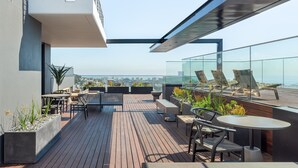 A rooftop terrace with outdoor seating, potted plants, and a view of the city skyline. - Bright Studio With City Views - No Load-shedding (Cape Town)